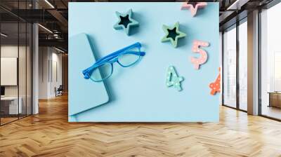 Child eyeglasses over blue pastel background. Optical store, glasses selection for kids, eye test, vision examination at optician concept. Top view, flat lay Wall mural