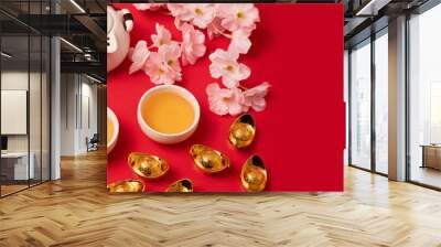 Chinese new year festival decoration over red background. Traditional lunar new year flat lay with green tea, red envelopes, gold ingots with text meaning fortune, prosperity, wealth. Top view Wall mural