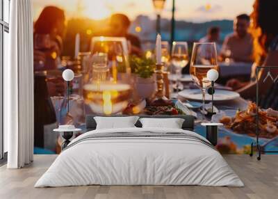 Close-up of a sunset dining setup outdoors, featuring glasses of wine and plates of gourmet food with people socializing in the background. Birthday, corporate party celebration. Wall mural