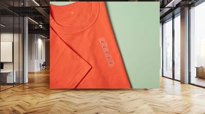 Showing size tag XL on orange t- shirt for selling in shop over green background Wall mural