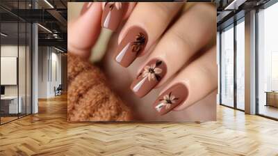 This stylish manicure showcases brown nail polish adorned with delicate floral designs, perfectly complementing a cozy sweater. Wall mural