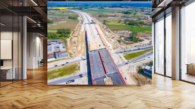 Aerial panorama top down view of an unfinished asphalt covered road with dirt, tracks of heavy machinery at construction site. The road to nowhere. Wall mural