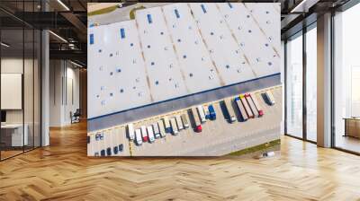 Aerial view of goods warehouse. Logistics center in industrial city zone from above. Aerial view of trucks loading at logistic center stock photo Wall mural