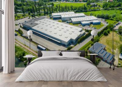 Aerial view of goods warehouse. Logistics center in industrial city zone from above. Aerial view of trucks loading at logistic center. View from drone. Wall mural