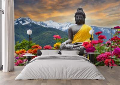 Buddha statue surrounded by colorful flowers with mountains and sunset in the background Wall mural