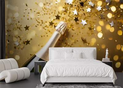 Champagne bottle with confetti stars, bokeh decoration and party streamers on golden background. Christmas, birthday or wedding concept. Flat lay. Wall mural