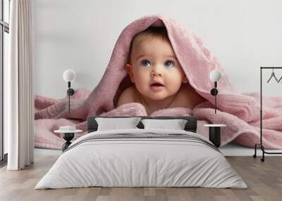 Baby girl under a pink towel, white background, portraying a comfortable childhood and curious model. Wall mural