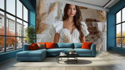 Beautiful young woman in a white wedding dress sitting on a bed in a stylish bedroom. Wall mural