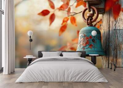 Metal bell adorned with a pattern on a branch with vibrant foliage in the autumn forest. Wall mural