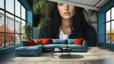 A young woman with long dark hair and striking blue eyes poses softly in a modern indoor setting, wearing a casual outfit that embodies a relaxed lifestyle.  Wall mural