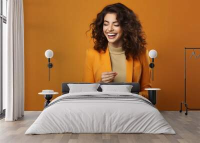 Happy young woman in yellow suit using smartphone isolated on orange, technology concept Wall mural