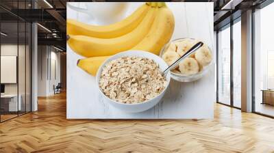 Bowl of oat flakes with sliced banana close-up on wooden table Wall mural