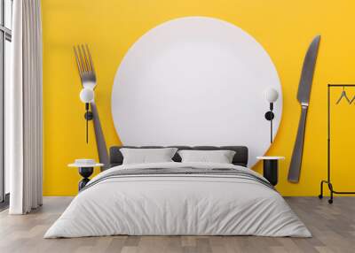 Clean empty white plate with knife and fork on yellow background place setting top view Wall mural