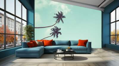 Two coconut palm trees hanging over sky background vintage color toned Wall mural