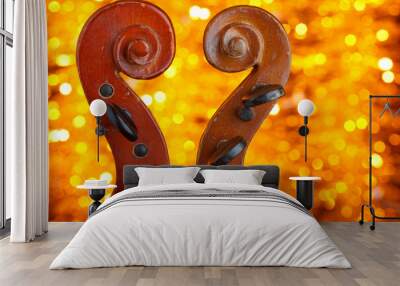 Two old vintage violin scrolls closeup with shiny golden glitter background Wall mural