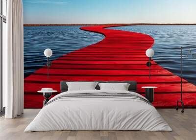 A vibrant red pathway stretches over serene water, creating a striking visual contrast against the clear blue sky. Wall mural