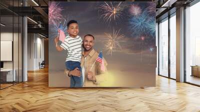 4th of July - Independence day of America. Happy man and his son holding national flags of United States against sky with fireworks Wall mural