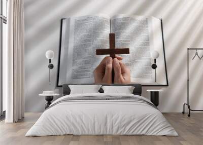 Above view of woman praying with wooden cross over Bible at white table Wall mural