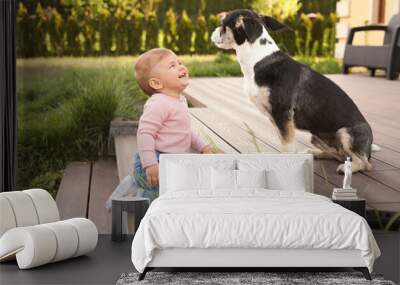 Adorable baby and furry little dog on wooden porch outdoors Wall mural