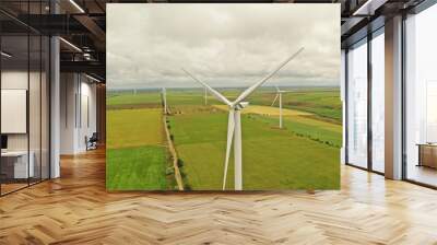 Aerial view of wind turbines in field on cloudy day Wall mural