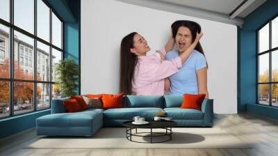 Aggressive young women fighting on light grey background Wall mural