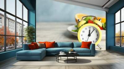 Alarm clock and healthy food on white wooden table, space for text. Meal timing concept Wall mural