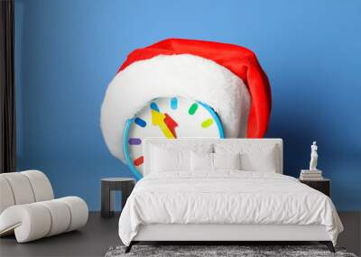 Alarm clock with Santa hat on blue background. New Year countdown Wall mural