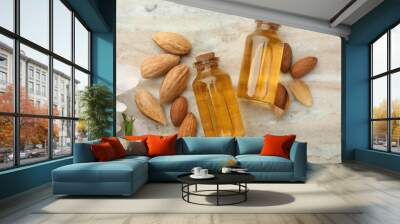 Almond oil in bottles, nuts and flowers on color marble table, flat lay Wall mural