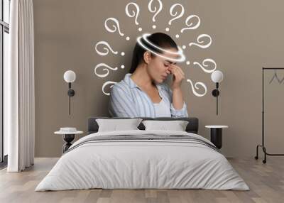 Amnesia concept. Woman surrounded by question marks trying to remember something on beige background Wall mural