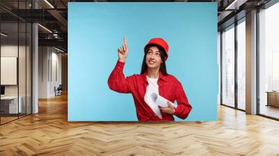 Architect in hard hat with draft pointing at something on light blue background Wall mural