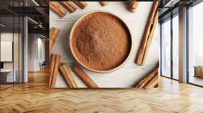 Aromatic cinnamon powder and sticks on white wooden table, flat lay Wall mural