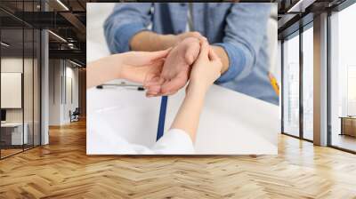 Arthritis symptoms. Doctor examining patient's wrist in hospital, closeup Wall mural