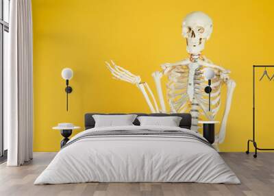 Artificial human skeleton model on yellow background. Space for text Wall mural