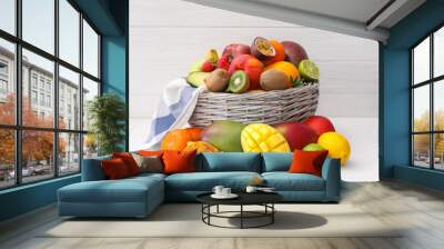 Assortment of fresh exotic fruits in basket on white wooden table Wall mural