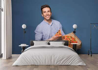 Attractive young man with delicious pizza on color background Wall mural