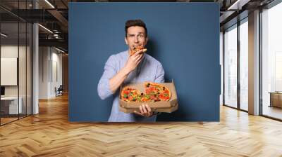 Attractive young man with delicious pizza on color background Wall mural