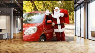 Authentic Santa Claus with bag full of presents near car outdoors Wall mural