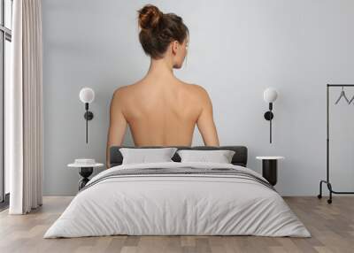 Back view of woman with perfect smooth skin on light grey background, space for text. Beauty and body care Wall mural