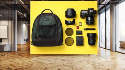 Backpack, camera and professional photographer's equipment on yellow background, flat lay Wall mural