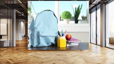 Backpack with different school stationery, apple and bottle of water on wooden table indoors Wall mural