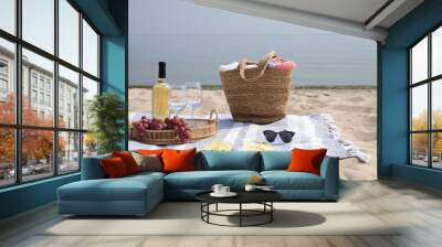 Bag, blanket, wine and other stuff for beach picnic on sandy seashore Wall mural