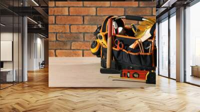 Bag with different tools for repair on white wooden table near brick wall. Space for text Wall mural