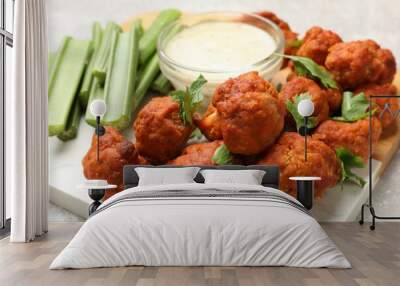 Baked cauliflower buffalo wings with celery and sauce on grey table, closeup Wall mural