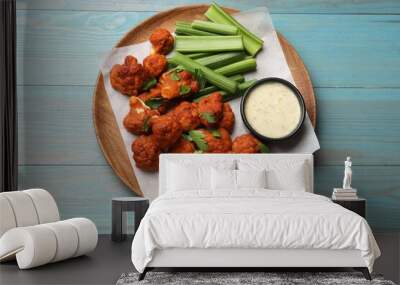 Baked cauliflower buffalo wings with celery and sauce on light blue wooden table, top view Wall mural