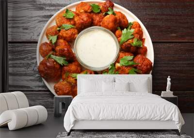 Baked cauliflower buffalo wings with parsley and sauce on wooden table, top view Wall mural