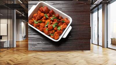 Baked cauliflower buffalo wings with parsley in baking dish on wooden table, top view. Space for text Wall mural