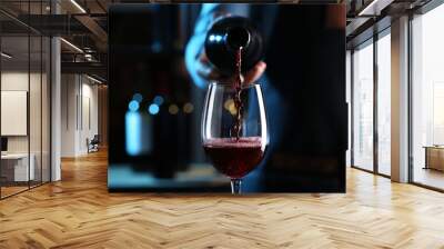 bartender pouring red wine from bottle into glass indoors, closeup Wall mural