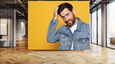 Bearded man fixing hair on orange background. Space for text Wall mural