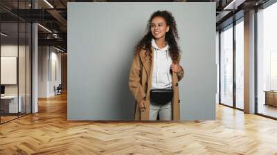 Beautiful African American woman with stylish waist bag on grey background, space for text Wall mural