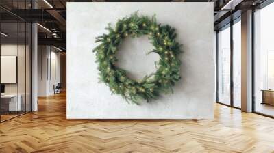 Beautiful Christmas wreath with festive lights on light wall Wall mural